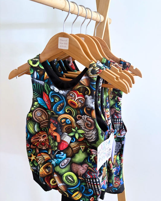 Colorful patterned baby romper on a wooden hanger against a white background